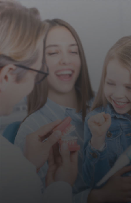 Doctor making his child patient smile by showing fake teeth set